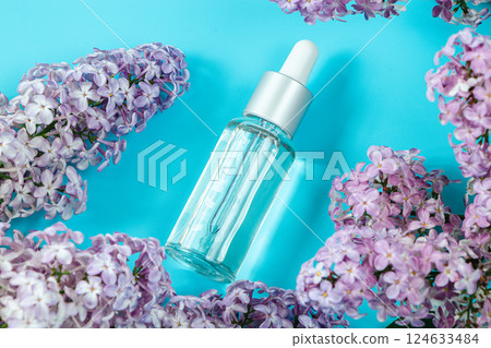 Skin care cosmetics on blue background. Moisturizing serum, cream and delicate lilac flowers. Spa and beauty treatment concept. Copy space. Skin care cosmetics on blue background. Moisturizing serum, cream and delicate lilac flowers. Spa and beauty treatment concept. Copy space. 124633484
