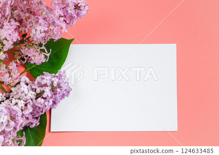 Lilac flowers and blank greeting card on coral background. Mockup for design, spring flatlay. Lilac flowers and blank greeting card on coral background. Mockup for design, spring flatlay. 124633485