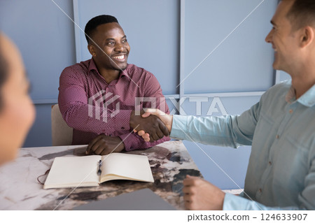 Two businessmen accomplishing formal meeting in office with handshake gesture Two businessmen accomplishing formal meeting in office with handshake gesture 124633907