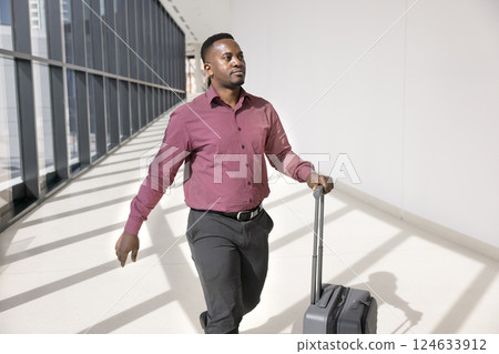 Man rolling his suitcase while moves confidently towards gate Man rolling his suitcase while moves confidently towards gate 124633912