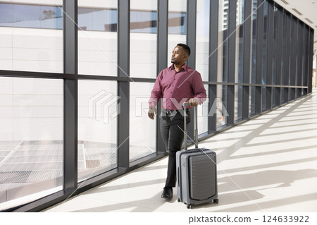 African man pulling rolling suitcase, hurrying to catch flight African man pulling rolling suitcase, hurrying to catch flight 124633922