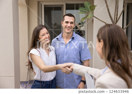 Married young couple shaking hands with female real estate agent 124633946
