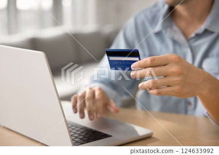 Man holds card using laptop purchasing via web store Man holds card using laptop purchasing via web store 124633992