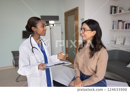 Happy young Black doctor telling good news to older patient 124633998