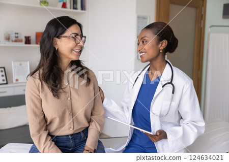 Happy supportive young African doc touching shoulder of senior woman 124634021