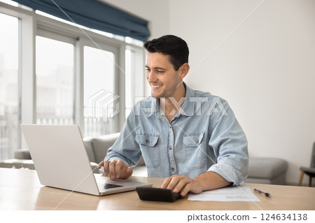 Young man managing family finances using laptop and calculator Young man managing family finances using laptop and calculator 124634138