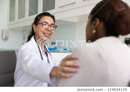 Happy positive senior doctor talking to young patient 124634139