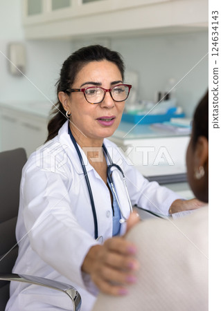 Compassionate mature doctor touching shoulder of female patient 124634143