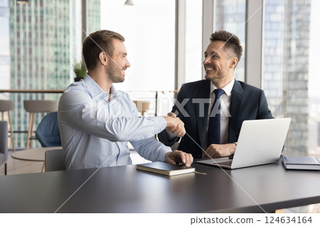 Two businessmen shaking hands in modern skyscraper office Two businessmen shaking hands in modern skyscraper office 124634164