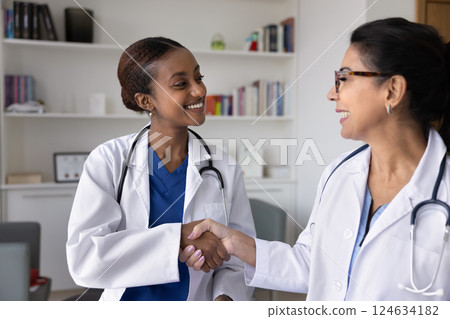 Happy young African American doctor shaking hands with senior colleague Happy young African American doctor shaking hands with senior colleague 124634182