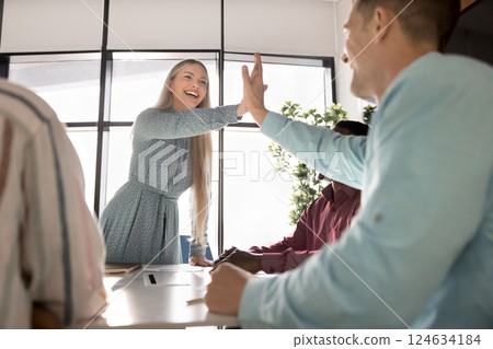 Cheerful European businesswoman gives high-five to male colleague Cheerful European businesswoman gives high-five to male colleague 124634184