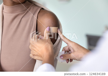 Hands of doctor sticking adhesive patch over shoulder of patient Hands of doctor sticking adhesive patch over shoulder of patient 124634189