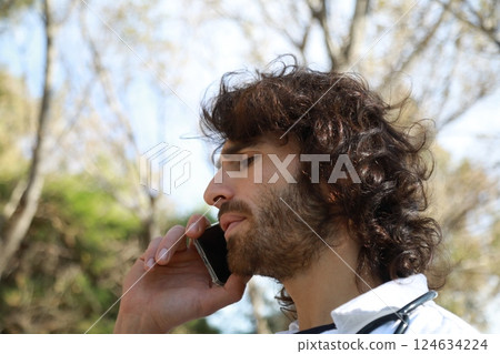 Long Hair Male Doctor Talks On The Phone Bad News Outside The Hospital 124634224