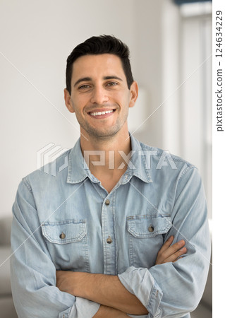 Handsome man in casual blue shirt posing indoor with arms-crossed 124634229