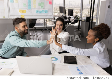 Multiethnic focus group of cheerful colleagues making high five gesture Multiethnic focus group of cheerful colleagues making high five gesture 124634257