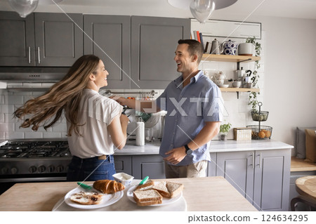 Joyful millennial married loving couple dancing in modern kitchen 124634295