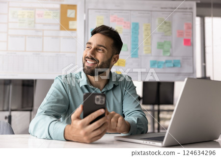 Happy project manager man using mobile phone at office workplace 124634296