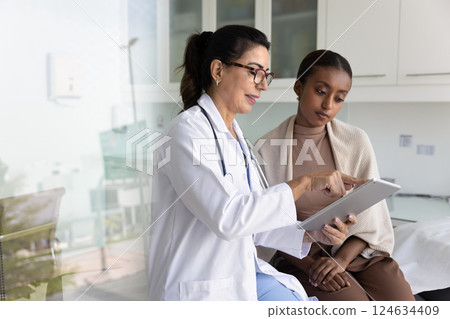Positive mature physician doctor showing checkup result to African patient Positive mature physician doctor showing checkup result to African patient 124634409