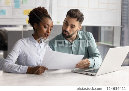 Two serious focused multiethnic coworkers reviewing financial legal document Two serious focused multiethnic coworkers reviewing financial legal document 124634411