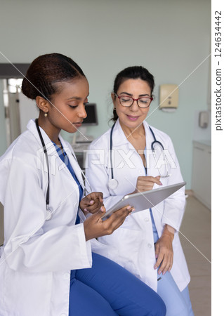 Positive senior doctor woman giving advice to young African colleague Positive senior doctor woman giving advice to young African colleague 124634442