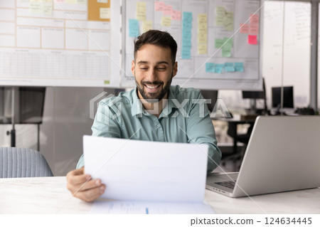 Positive satisfied Hispanic business professional man reading paper report 124634445