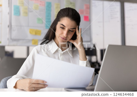 Thoughtful concerned Latin business professional woman reading financial document Thoughtful concerned Latin business professional woman reading financial document 124634468