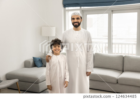Arabic father and little son standing together in living room Arabic father and little son standing together in living room 124634485