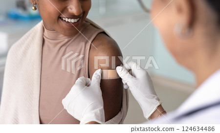 Female doctor sticking plaster on shoulder of patient Female doctor sticking plaster on shoulder of patient 124634486