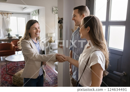 Happy couple shaking hands with female realtor 124634491