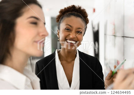 Cheerful beautiful young African businesswoman standing at whiteboard 124634495