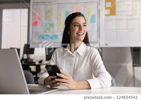 Happy young Latin businesswoman using digital gadgets at office workplace 124634542