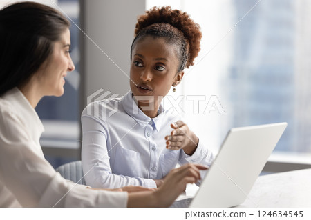 Serious young African businesswoman talking to positive female colleague 124634545