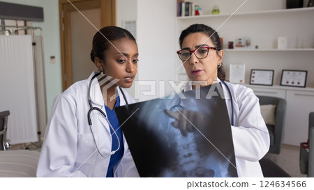 Mature Caucasian doctor and young African practitioner reviewing Xray image 124634566