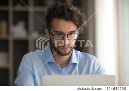 Closeup serious millennial man in glasses concentrated on notebook screen 124634568