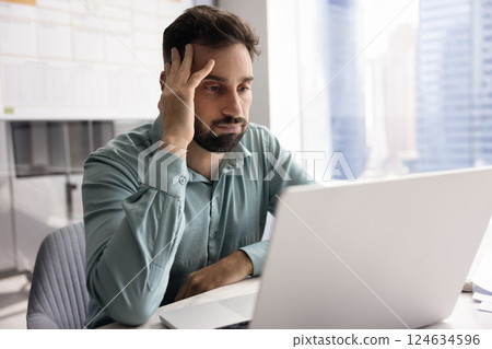 Tired annoyed Latin businessman touching head at laptop Tired annoyed Latin businessman touching head at laptop 124634596