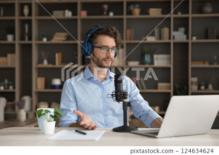 Young man in headphones speak in microphone before notebook screen Young man in headphones speak in microphone before notebook screen 124634624