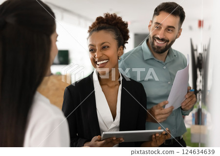 Happy diverse business partners talking at whiteboard, discussing collaboration Happy diverse business partners talking at whiteboard, discussing collaboration 124634639
