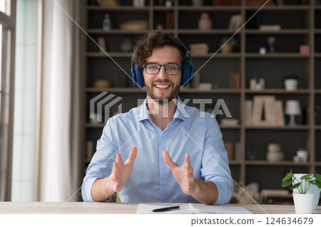 Happy young male in headset speaking at camera at workplace 124634679