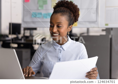 Happy African business professional woman in casual using financial app 124634701