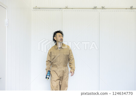 A man in overalls walking through a warehouse 124634770
