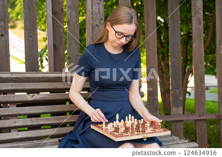 Caucasian woman playing chess outdoors. 124634916