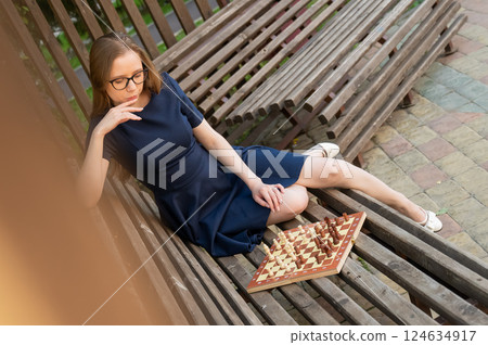 Caucasian woman playing chess outdoors. 124634917