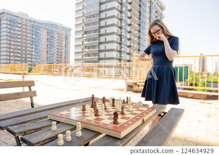 Caucasian woman playing chess outdoors. 124634929