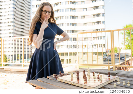 Caucasian woman playing chess outdoors. 124634930