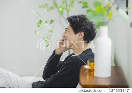 一個在客廳裡使用智能手機的人 124635347