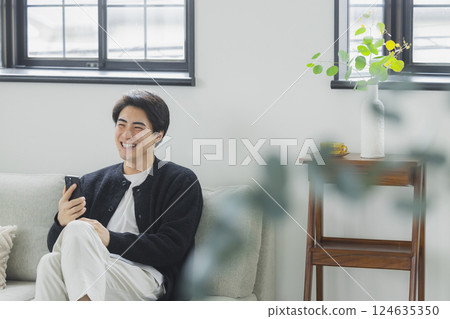 A man who uses a smartphone in the living room 124635350