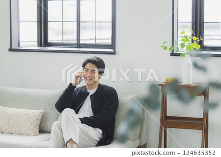 一個在客廳裡使用智能手機的人 124635352