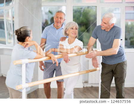 Active old attendees of ballet courses communicating cheerfully at ballet-barre Active old attendees of ballet courses communicating cheerfully at ballet-barre 124637556