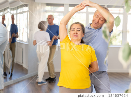 Senior man dancing bachata with female partner during group class 124637624