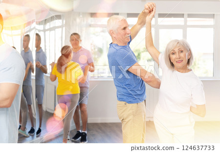 Elderly man in dance hall with female partner and dances Latin rumba. Hobby, healthy lifestyle concept Elderly man in dance hall with female partner and dances Latin rumba. Hobby, healthy lifestyle concept 124637733